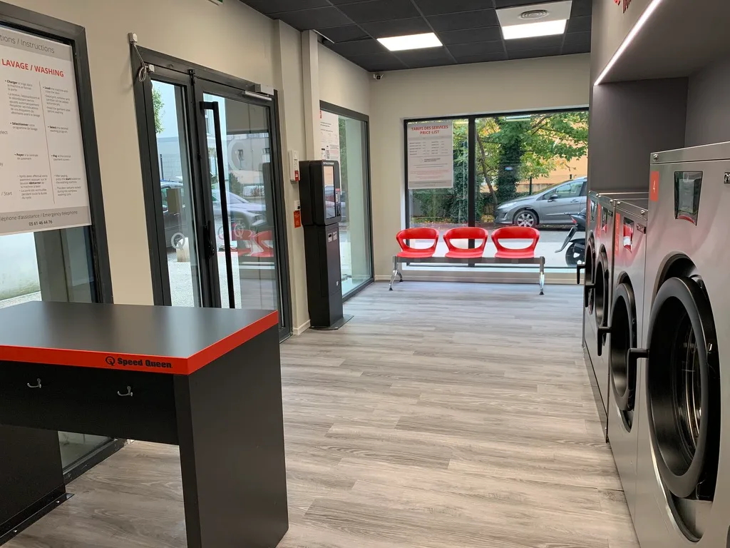 Área do cliente com mesa de dobragem e instruções, lavanderia Croix-Daurade Toulouse