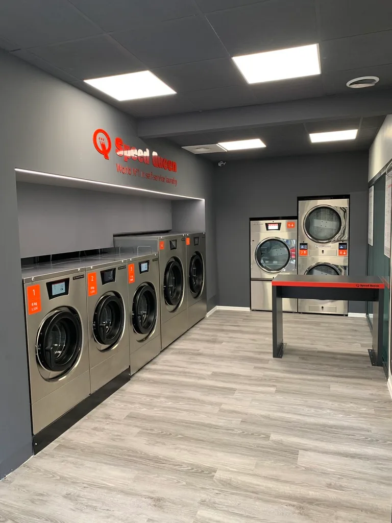Vista geral do interior da lavanderia Speed Queen Croix-Daurade, máquinas e iluminação LED